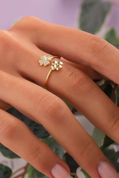 a woman's hand wearing a gold ring with flowers on it