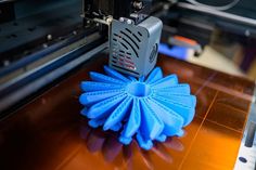 a blue duster sitting on top of a wooden table next to a printer machine