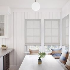 a kitchen with white walls and wooden flooring next to a window covered in blinds