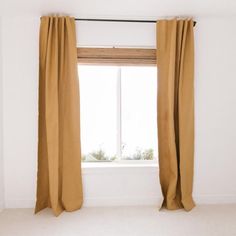 an empty room with a window and tan curtains