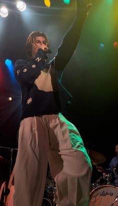 a man standing on top of a stage with his arms in the air while holding a microphone