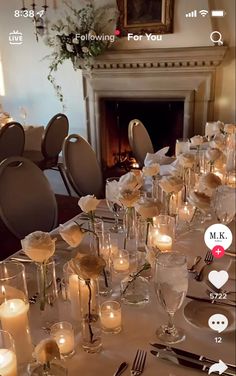 a long table is set with silverware and candles in front of a fire place