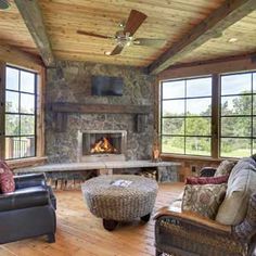 a living room filled with furniture and a fire place in the middle of a wooden floor