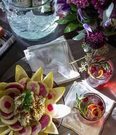 a table topped with plates and glasses filled with food next to vases full of flowers