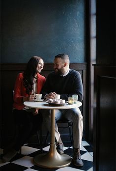 a man and woman sitting at a table with food in front of them, smiling