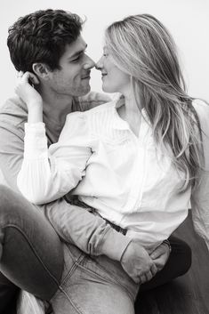 a man and woman sitting next to each other on a couch kissing in black and white