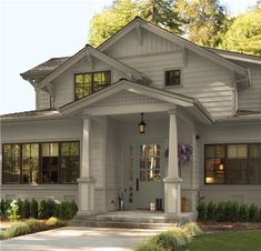 a white house with red front door and two large windows on the side of it