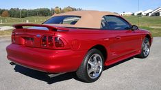 the back end of a red sports car parked in a parking lot next to a house