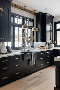 a large kitchen with black cabinets and white counter tops is pictured in this image, there are two chandeliers hanging from the ceiling