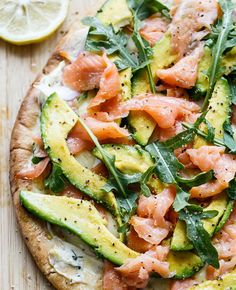 a pizza with salmon, cucumber and spinach on it