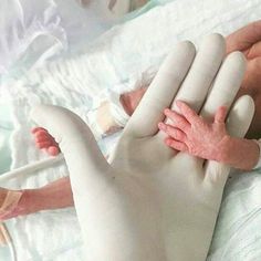 a baby is being held by an adult in a hospital bed with the hand on it's head