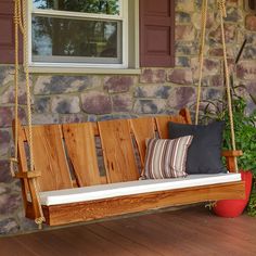 a wooden porch swing with pillows on it