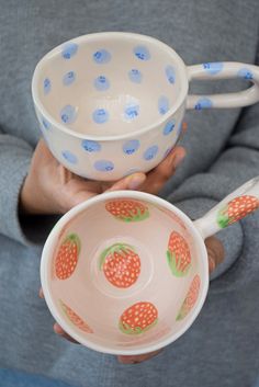 a person holding two bowls and spoons in their hands, with polka dot designs on them