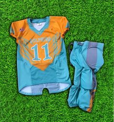 an orange and blue football uniform sitting on top of green grass next to a pair of pants