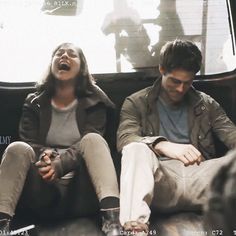 a man and woman sitting on the back of a bus looking up at something in the air