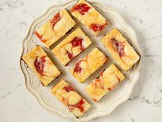 several pieces of cake sitting on top of a white and beige plate next to a marble counter