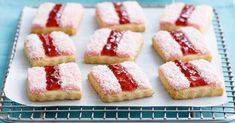 strawberry shortbreads with powdered sugar and jelly filling on a baking sheet, ready to be baked