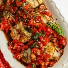 a white plate topped with fish covered in tomatoes