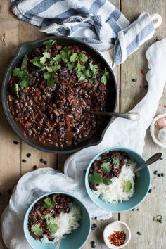 three bowls filled with beans and rice on top of a wooden table