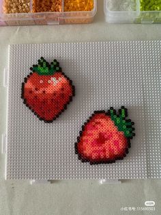 two plastic strawberries sitting on top of a table next to some beads and candy