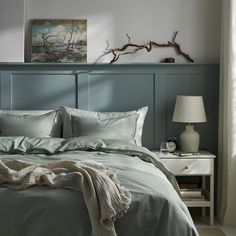 a bed with two lamps on either side of it and a painting above the headboard