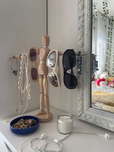 a wooden mannequin next to a mirror with sunglasses on it and a bowl of cereal