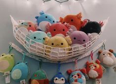 a bunch of stuffed animals are in a basket with string lights hanging from the ceiling