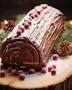 a log cake with chocolate frosting and berries on top, surrounded by pine cones