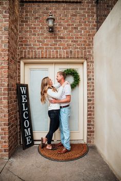 a man and woman standing in front of a welcome sign