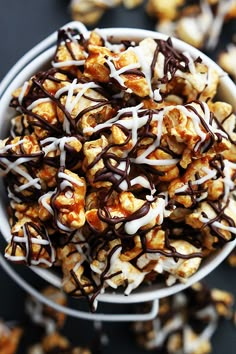 a bowl filled with popcorn covered in chocolate and drizzled with white icing