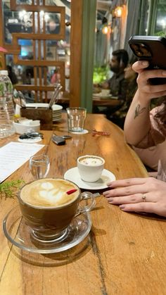 a woman sitting at a wooden table with a cup of coffee in front of her