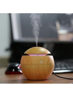 an air humider sitting on top of a wooden table next to a laptop computer