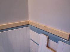 the corner of a bathroom that is being painted white and has blue trim on it