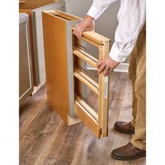 a man is holding the door to his kitchen cabinet that has been built into the floor