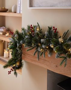 christmas garland with lights and pine cones hanging on the mantle