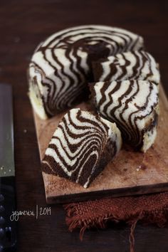 a zebra print cake sitting on top of a wooden cutting board