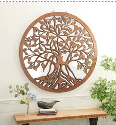 a wooden wall hanging with a tree cutout on it's side table in front of a white wall