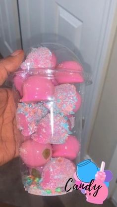 a person holding a plastic container filled with pink and blue sprinkle covered donuts