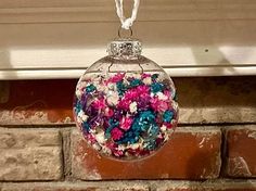 a glass ornament hanging from a window sill filled with colorful confetti