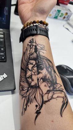 a woman's arm with a black and white tattoo design on it, next to a laptop