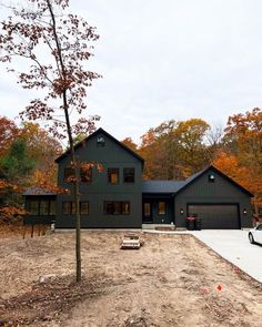 a car is parked in front of a large house with lots of trees around it