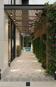 an outdoor walkway with plants and flowers on the side of it, next to a swimming pool