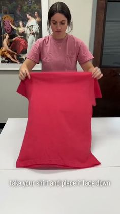 a woman is holding up a pink piece of cloth on a white surface with the words, take your shirt and place it face down