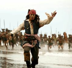 a group of men in pirate costumes running on the beach