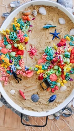 a bowl filled with lots of different colored beads and sea life on top of a wooden table