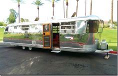 a silver trailer parked on the side of a road with palm trees in the background