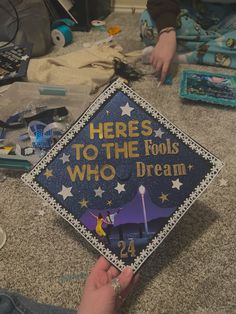 someone is holding up a graduation cap that says heres to the fools who dream