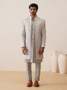 Grey Color Sequnied & resham embroidered IndoWestern Sherwani for the Groom and his squad family & firends. Crafted from the most luxurious silk, this item will have you feeling like a royal king. This indo-western sherwani, including an open sherwani at the front and an inside sleevless kurta paired with slim-cut trousers. Note: Some color variations may occur owing to photography causes. Up to 1 inch of measurement fluctuation is possible. COST INCLUDES SHERWANI,TROUSER & INNER JACKET Embroidered Sherwani For Groom In Transitional Season, Transitional Embroidered Sherwani For Groom, Groom's Transitional Sherwani With Chikankari Embroidery, Eid Nehru Jacket With Intricate Embroidery For Groom, Bollywood Bandhgala With Chikankari Embroidery For Groom, Embroidered Sherwani For Groom, Bandhgala With Chikankari Embroidery For Groom At Festivals, Groom's Kurta With Intricate Embroidery, Embroidered Kurta For Groom In Transitional Season