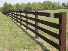 a wooden fence in the middle of a grassy field