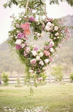 a heart shaped wreath with flowers hanging from it's sides and the words above it